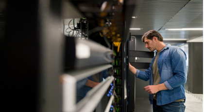 a man is looking into a set of computers in a data center showing the type of setting a Generac 2500 MW generator would back up